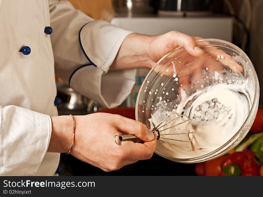 Man s hand whisk whips cream in a glass dish