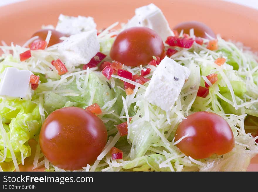 Fresh salad with feta and tomatoes on orange plate