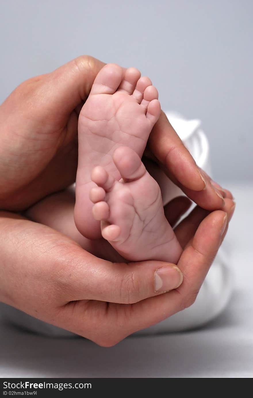 Feet of the baby in hands of the mother