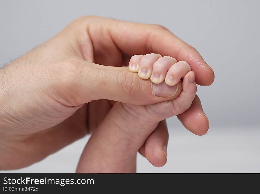 Handle of the baby clenching the thumb of the father