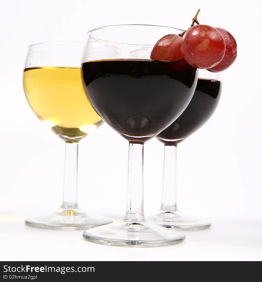 Red and white wine in wineglasses with three red grapes on white background