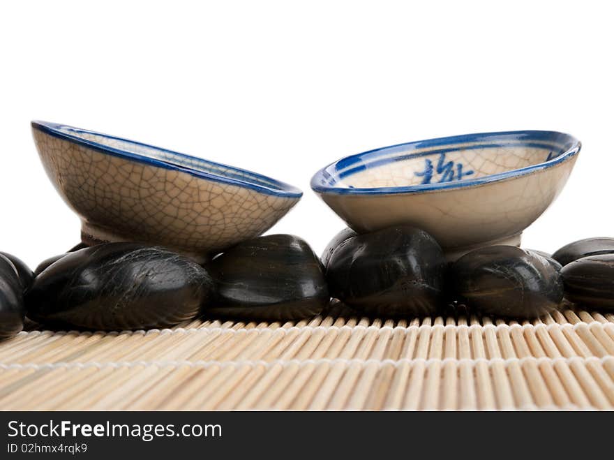 Two cups and stones on mat  isolated in white