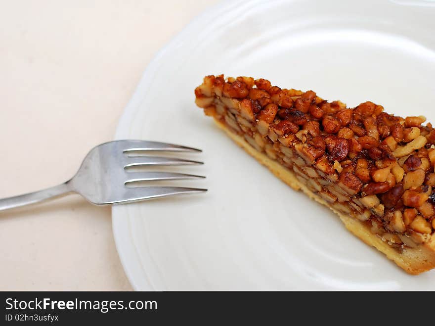 A single slice of hazel nut tart on white plate. For concepts such as food and beverage, diet and nutrition, and healthy eating.