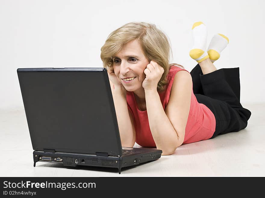 Senior woman lying down on white wooden floor and using a laptop,see more in <a href=http://www.dreamstime.com/people-on-couch-or-wooden-floor-rcollection11965-resi828293>People on couch or wooden floor</a>. Senior woman lying down on white wooden floor and using a laptop,see more in <a href=http://www.dreamstime.com/people-on-couch-or-wooden-floor-rcollection11965-resi828293>People on couch or wooden floor</a>