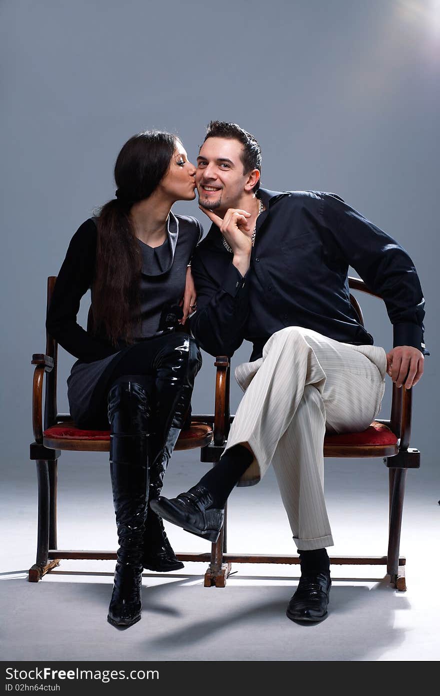 Young woman kissing a man in a cheek on the bench. Young woman kissing a man in a cheek on the bench.