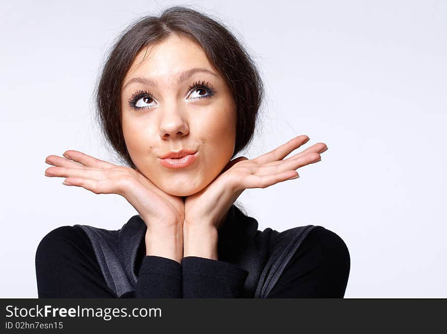 Portrait of a beautiful happy young girl looking away and holding her open palms under her chin. Portrait of a beautiful happy young girl looking away and holding her open palms under her chin