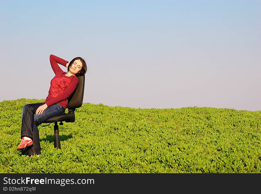 Girl in a spring field on a chair. Girl in a spring field on a chair