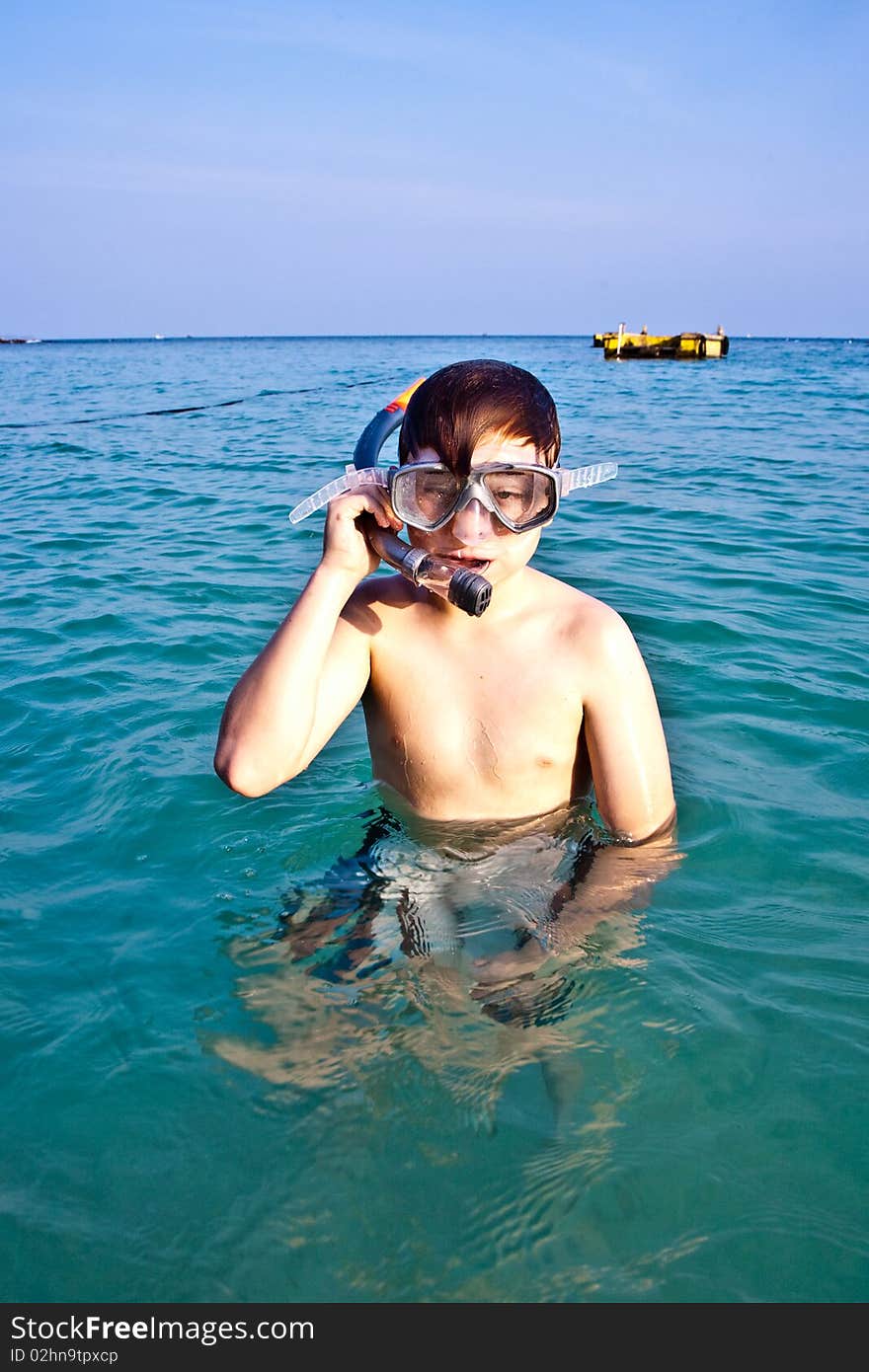 Young boy is standing in the beautiful clear sea, enjoying the water and starts snorkeling. Young boy is standing in the beautiful clear sea, enjoying the water and starts snorkeling