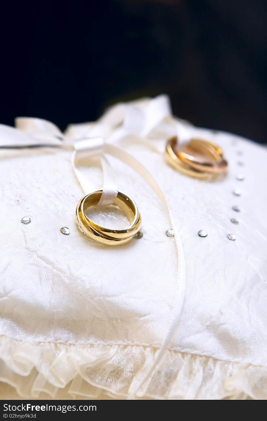 Gold wedding rings on a satiny pillow in heart form