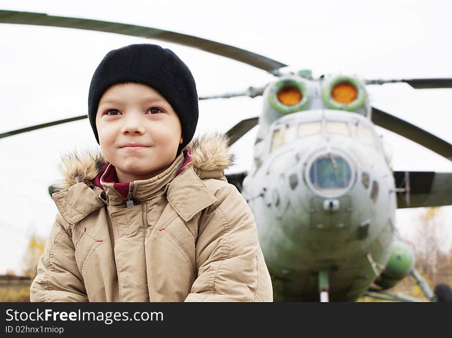 Young boy standing in front of single helicopter and dreaming about flying. Young boy standing in front of single helicopter and dreaming about flying