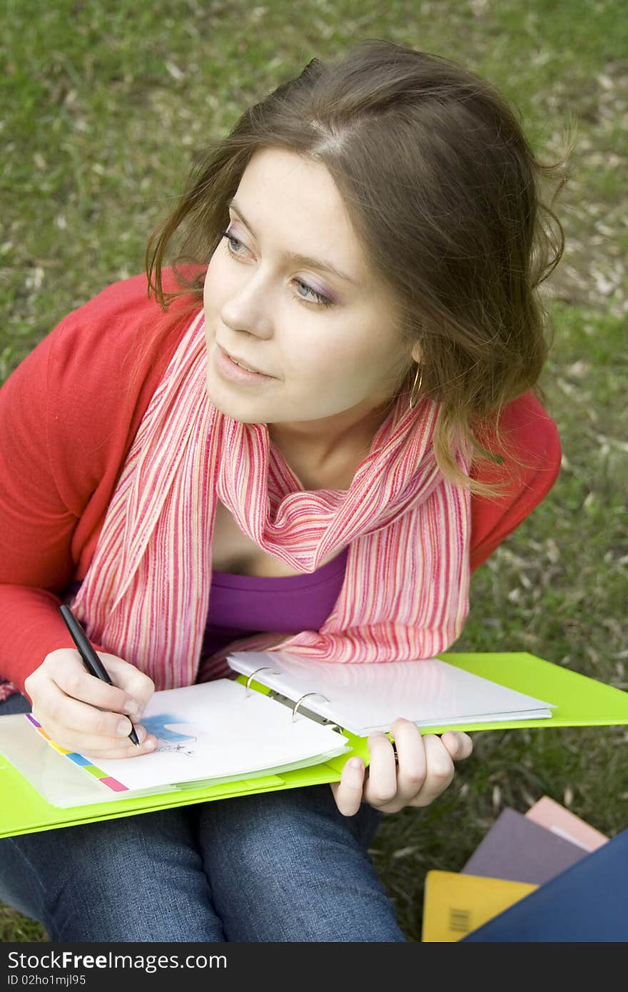 Young beautiful woman sitting on the grass in the park and draws sketches. Student. Young beautiful woman sitting on the grass in the park and draws sketches. Student