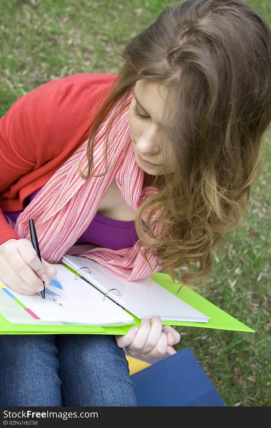 Young beautiful woman sitting on the grass in the park and draws sketches. Student. Young beautiful woman sitting on the grass in the park and draws sketches. Student