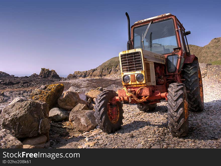 Old, rusty tractor on a pebble beach