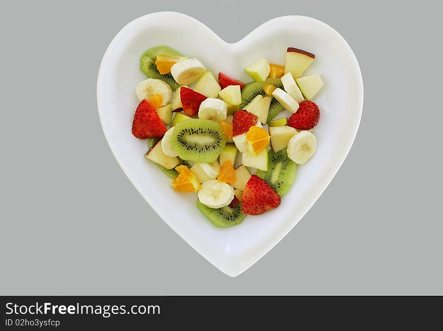 Five fresh fruits in a fruit salad in heart shaped dish. Five fresh fruits in a fruit salad in heart shaped dish