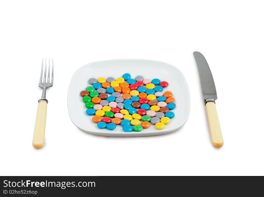 Knife, plug and plate with  lot of multi-coloured tablets on white background