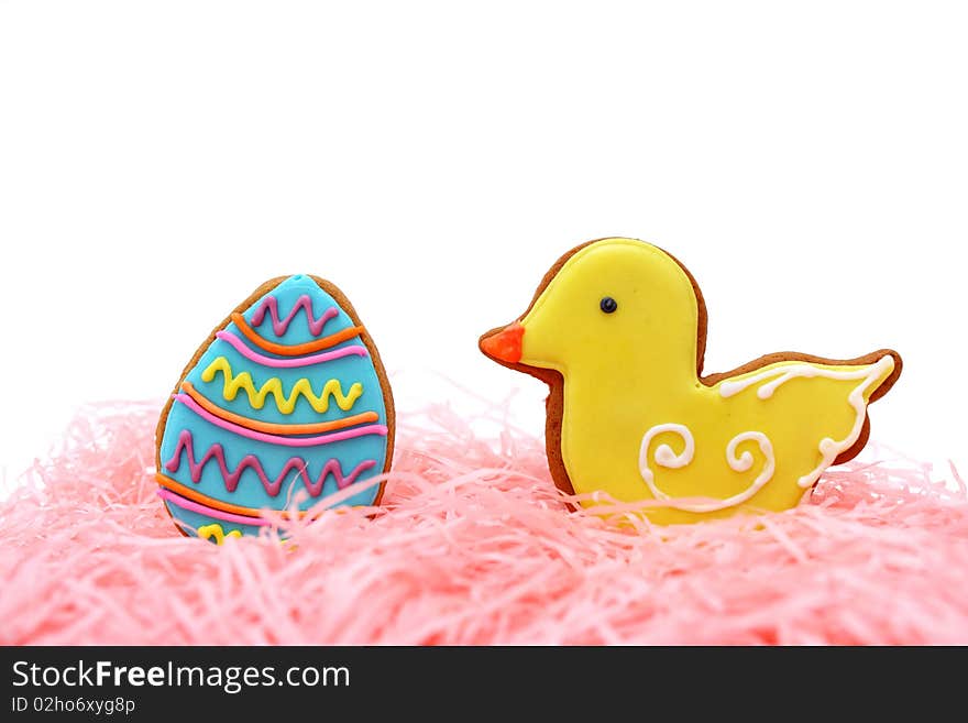 Close up of easter egg and duck cookies on pink ribbons over white background. Close up of easter egg and duck cookies on pink ribbons over white background.