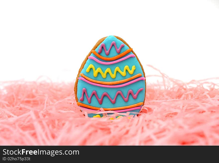 Close up of easter egg cookie on pink ribbons over white background.