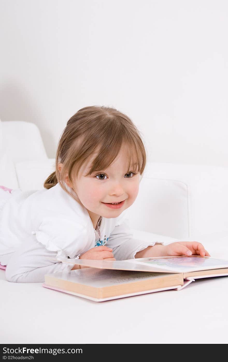 Sweet happy little girl reading book