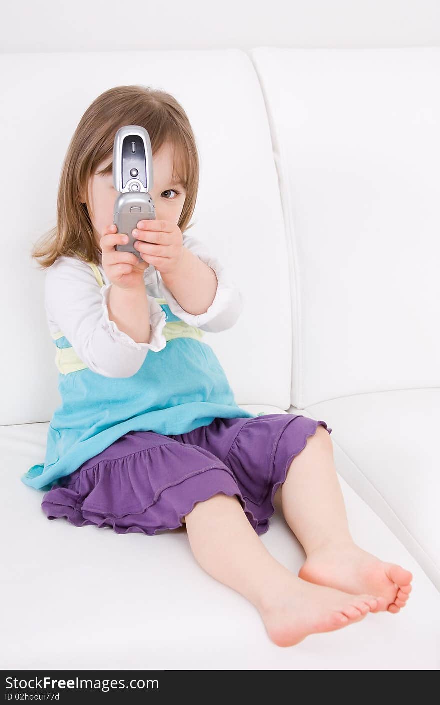 Little girl with mobile phone on sofa