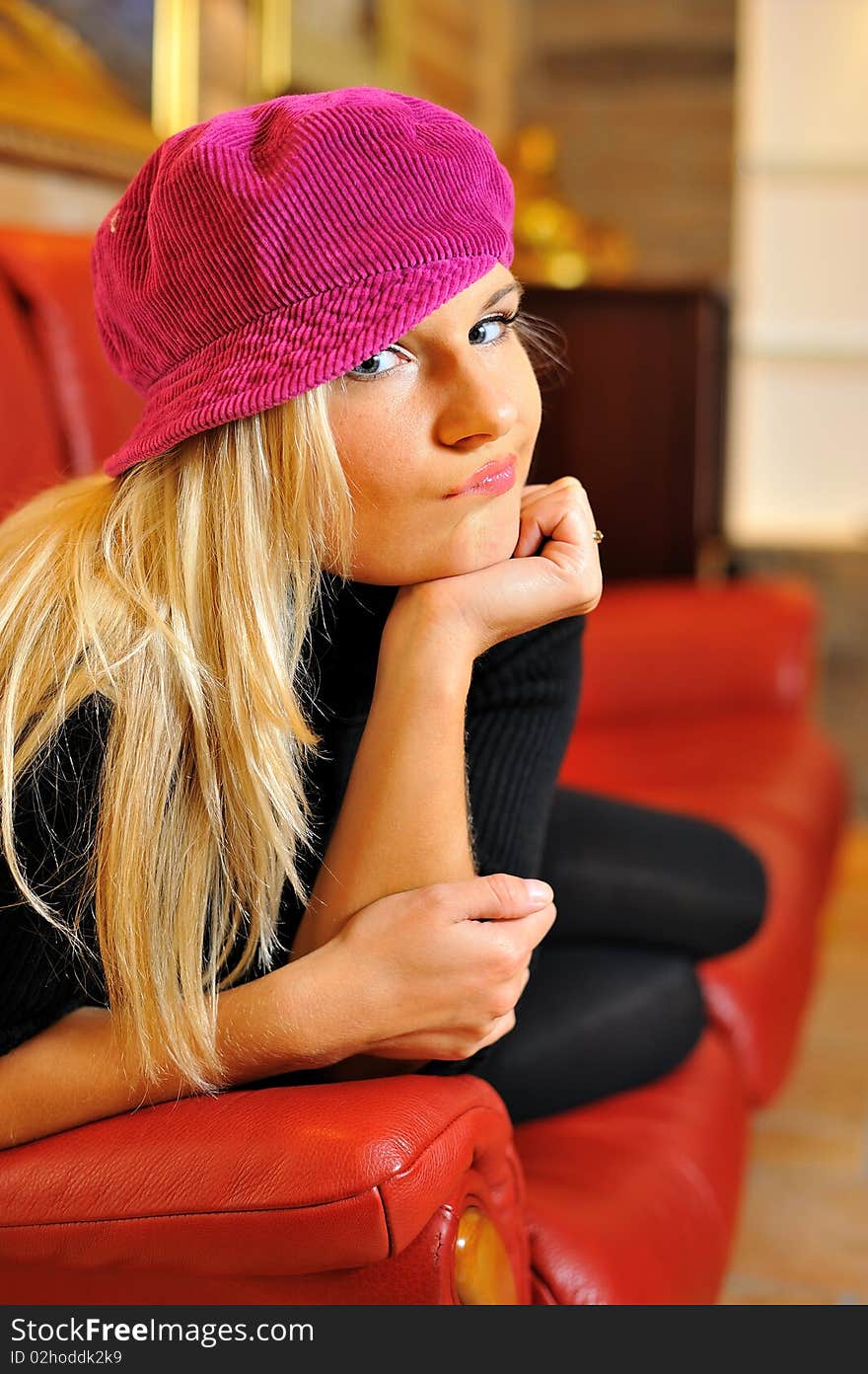 Young funny casual blond woman on red sofa