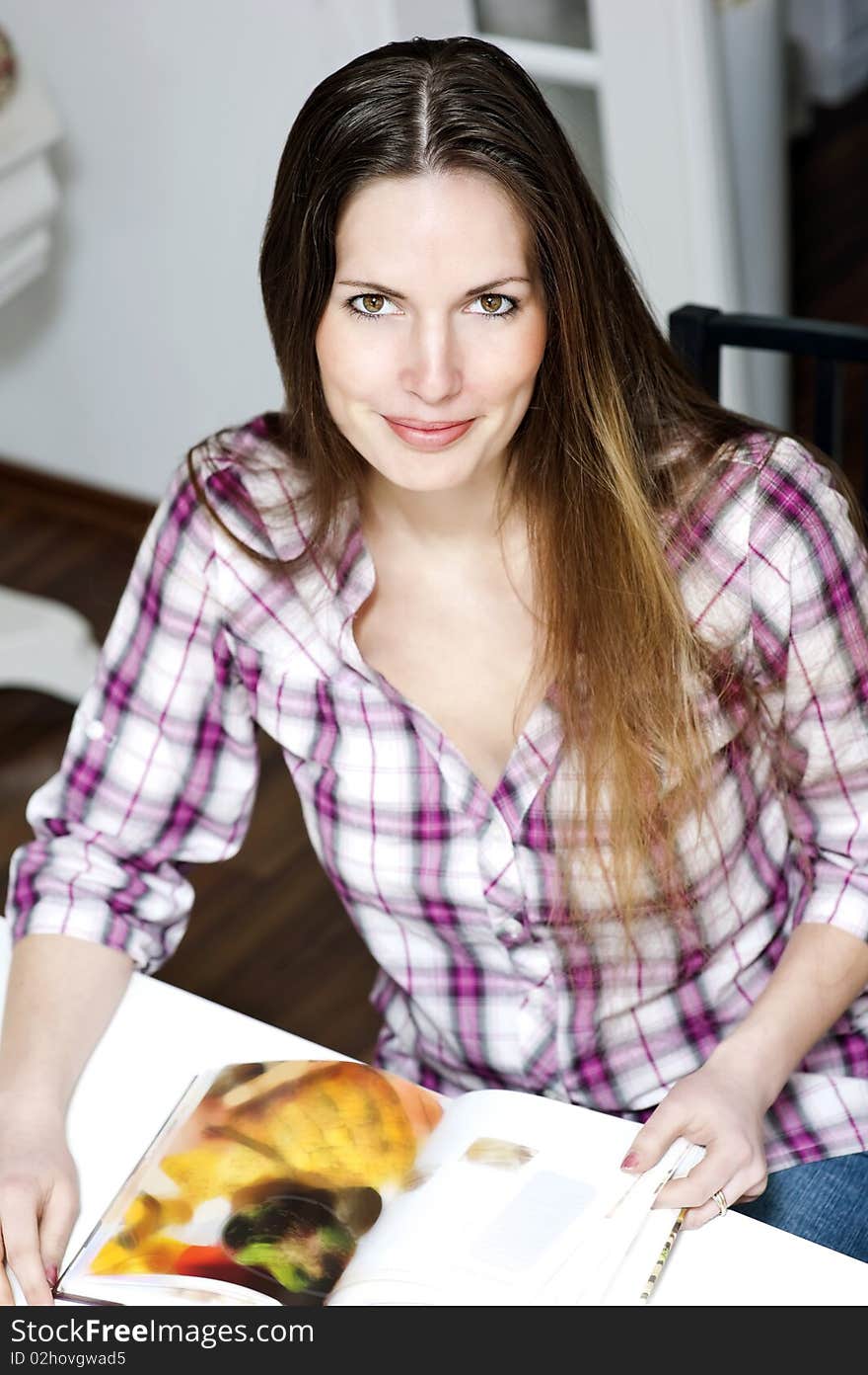 Young woman sitting at the table with a book. Young woman sitting at the table with a book