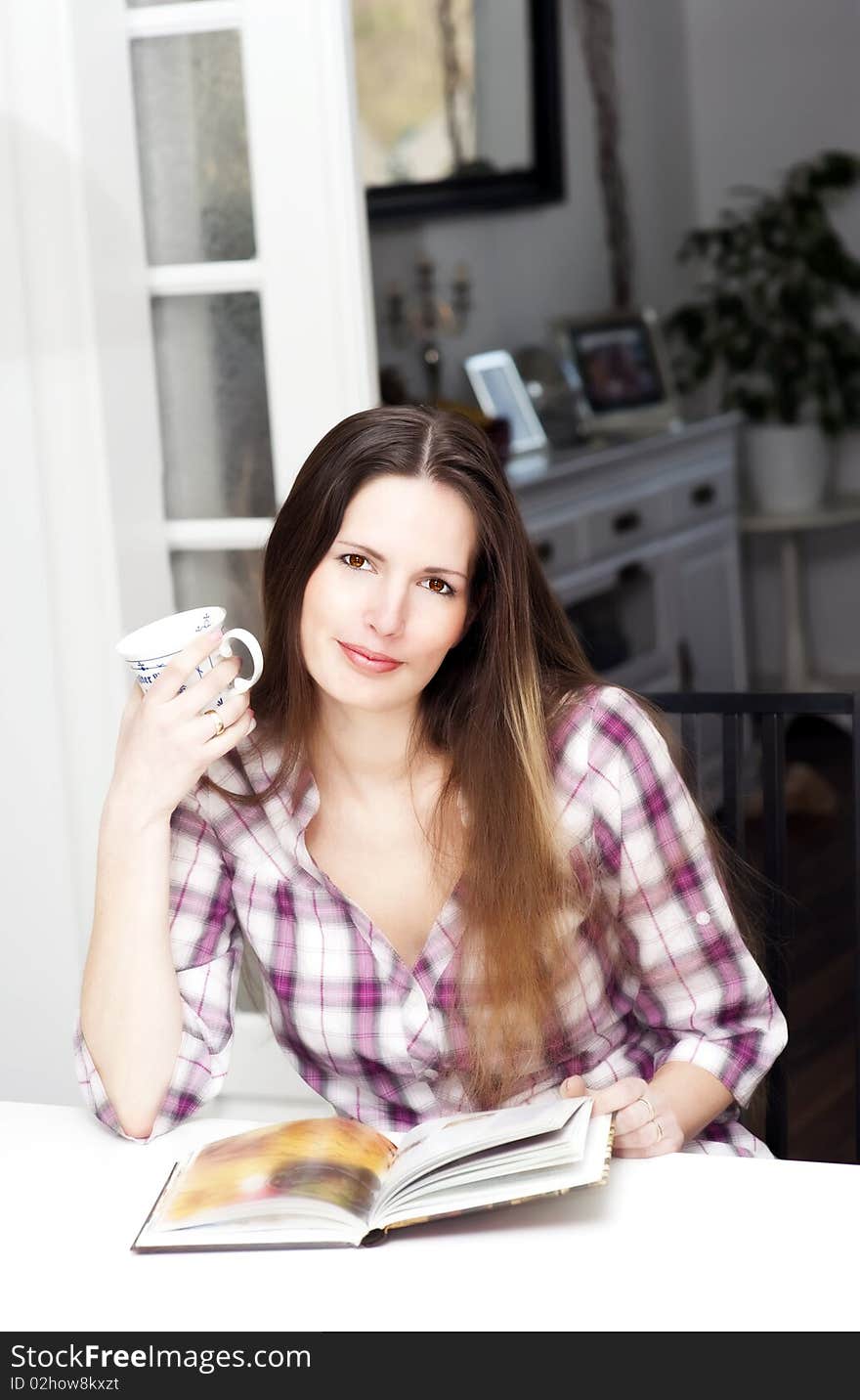 Young woman reading  a book and drinking a coffee. Young woman reading  a book and drinking a coffee