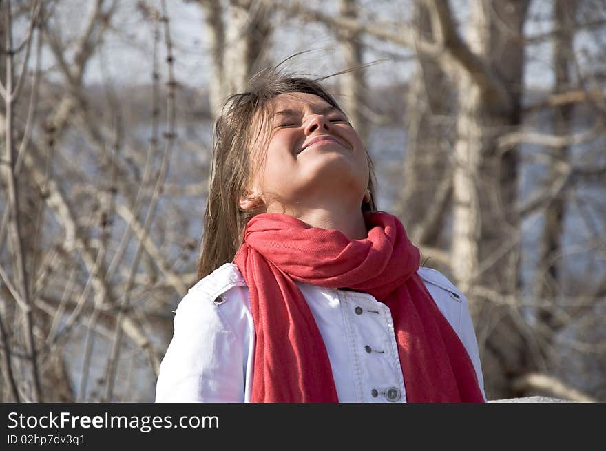 Portrait of a young beautiful girl in a red scarf. Outdoor scene. Close up.