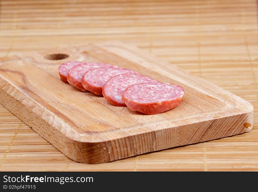 Many piece of sausage on brown kitchen board