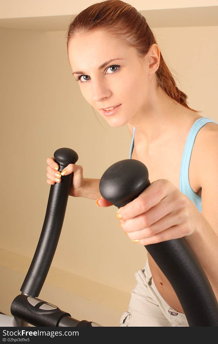 The young woman goes in for sports on training apparatus