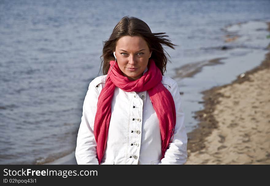 A beautiful young girl walking on the beach in spring. She looks into the camera with green eyes.