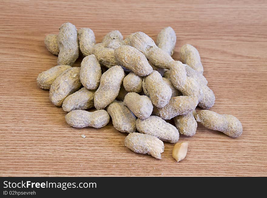 Whole salted peanuts, on light wood background