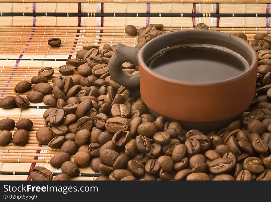 A cup of coffee surrounded by coffee beans