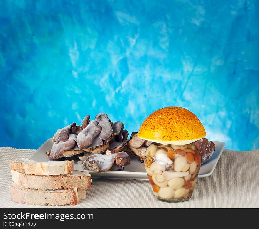 Bread near a jar of mushrooms on a blue background