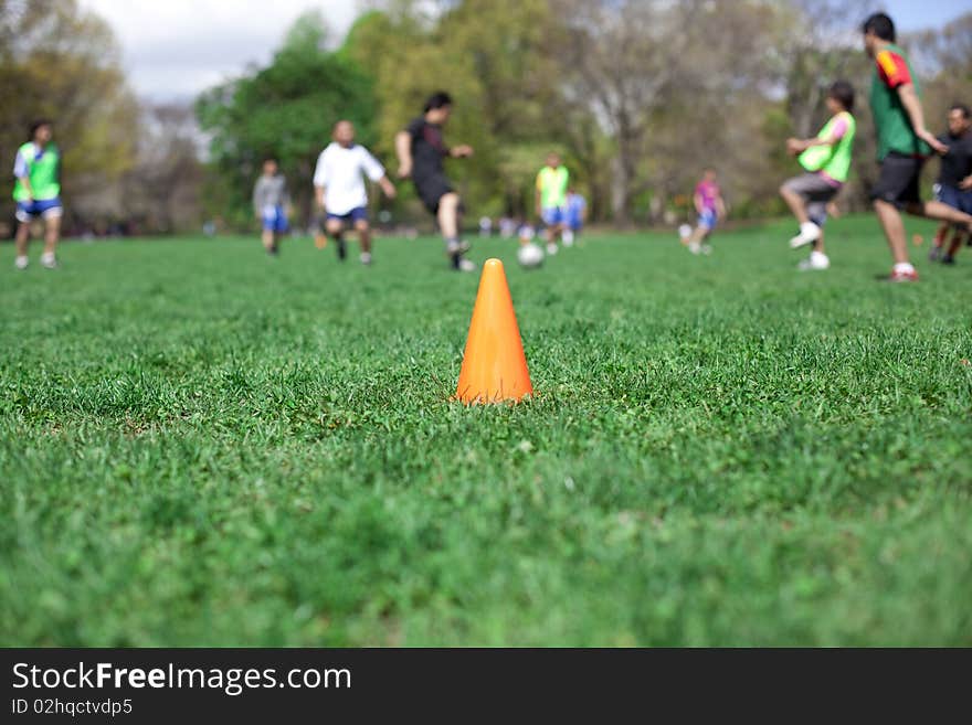 Orange safety cone in the grass in the soccer field. Shallow depth of field