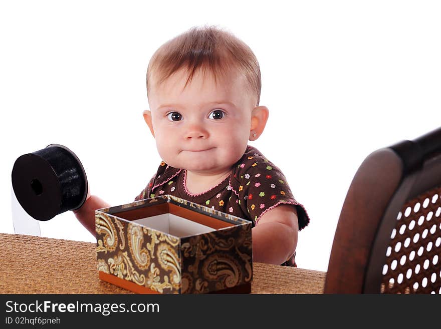 A new-standing baby playing with articles on the furniture that gives her balance.  Isolated on white. A new-standing baby playing with articles on the furniture that gives her balance.  Isolated on white.