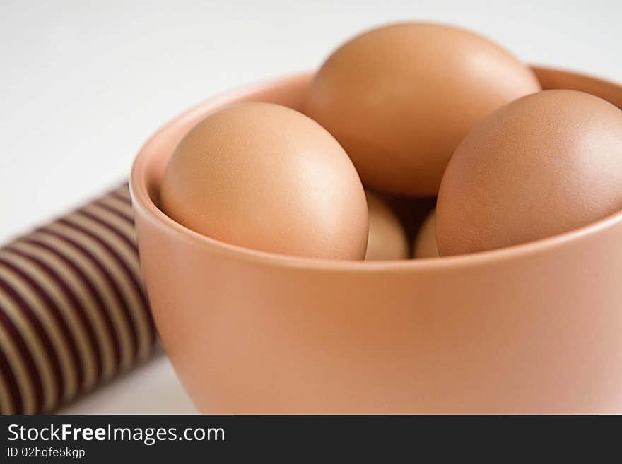 brown eggs in a big brown coffee cup with a stripped napkin beside it on white background. brown eggs in a big brown coffee cup with a stripped napkin beside it on white background