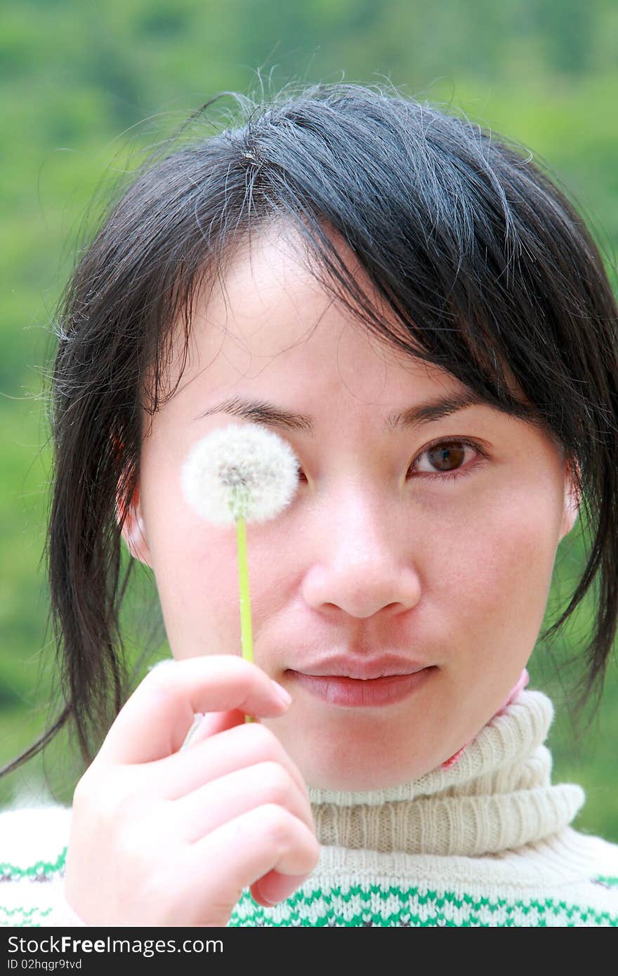 Portrait of Chinese girl covering her eye with dandelion. Portrait of Chinese girl covering her eye with dandelion