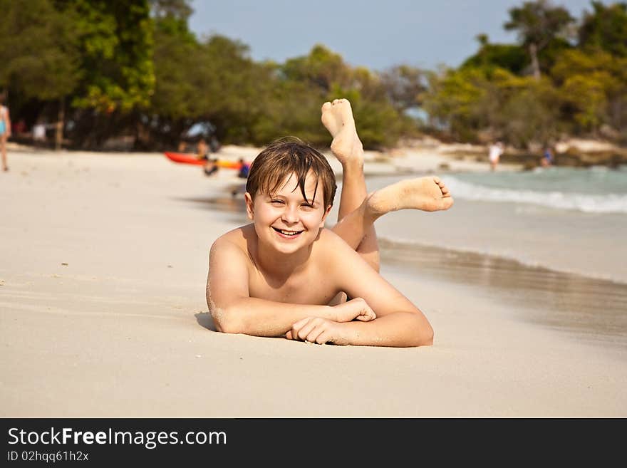 Boy is lying at the beach and enjoying the warmness of the water and looking self confident and happy. Boy is lying at the beach and enjoying the warmness of the water and looking self confident and happy