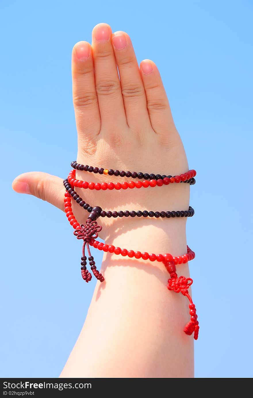 Prayer beads in her hands.Against the background of blue sky.