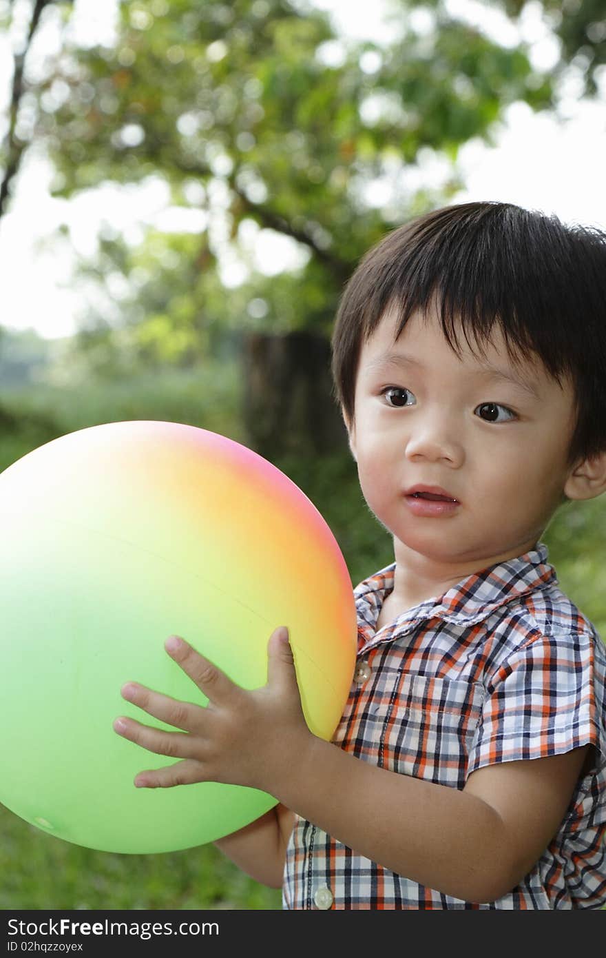 An Asian boy playing with a colorful ball at a public park. An Asian boy playing with a colorful ball at a public park