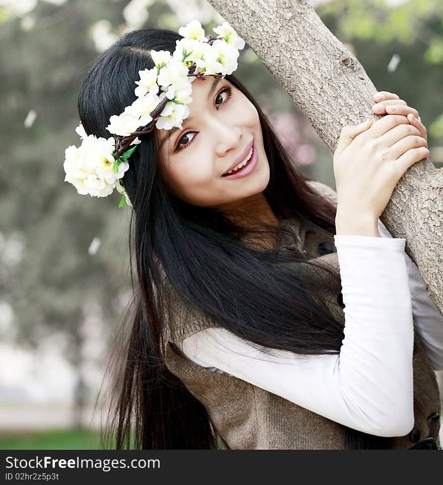 Smiling Asian girl with garlands under cherry tree. Smiling Asian girl with garlands under cherry tree.