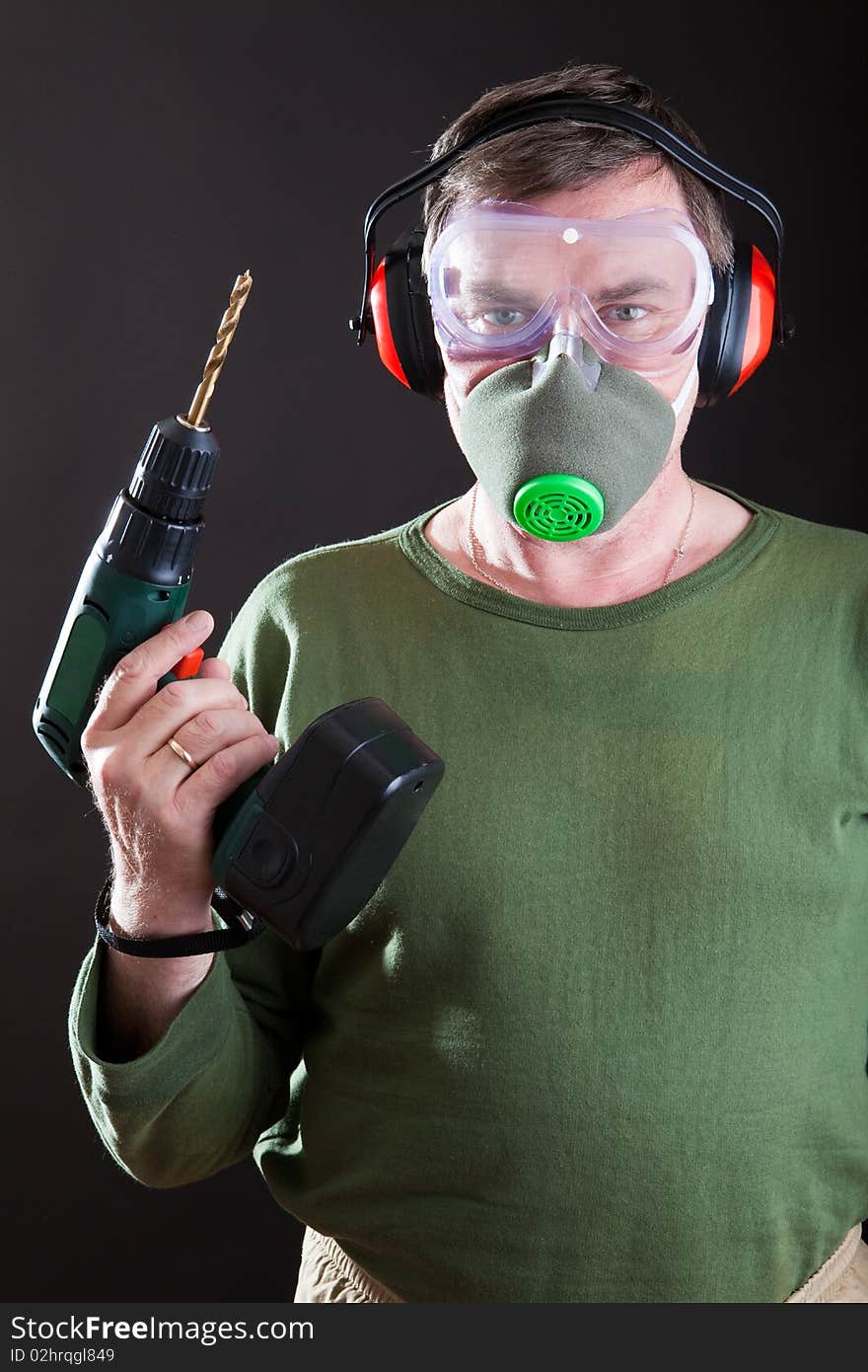 Man with a drill in a mask and a respirator. Man with a drill in a mask and a respirator