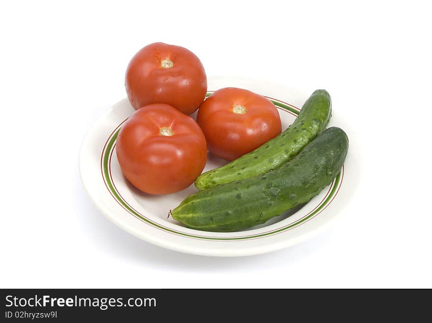 Tomatoes, cucumbers and radishes on a plate isolated on a white background. Tomatoes, cucumbers and radishes on a plate isolated on a white background