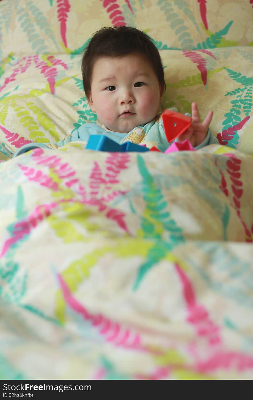 Lovely Chinese baby playing toy in the bed. Lovely Chinese baby playing toy in the bed