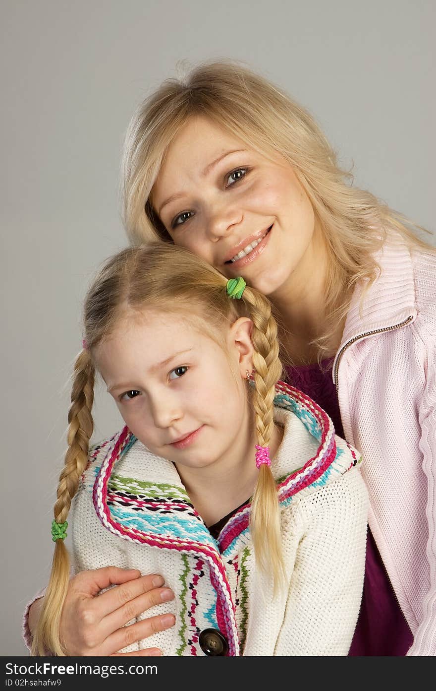 Happy woman with daughter, studio shot, gray background. Happy woman with daughter, studio shot, gray background