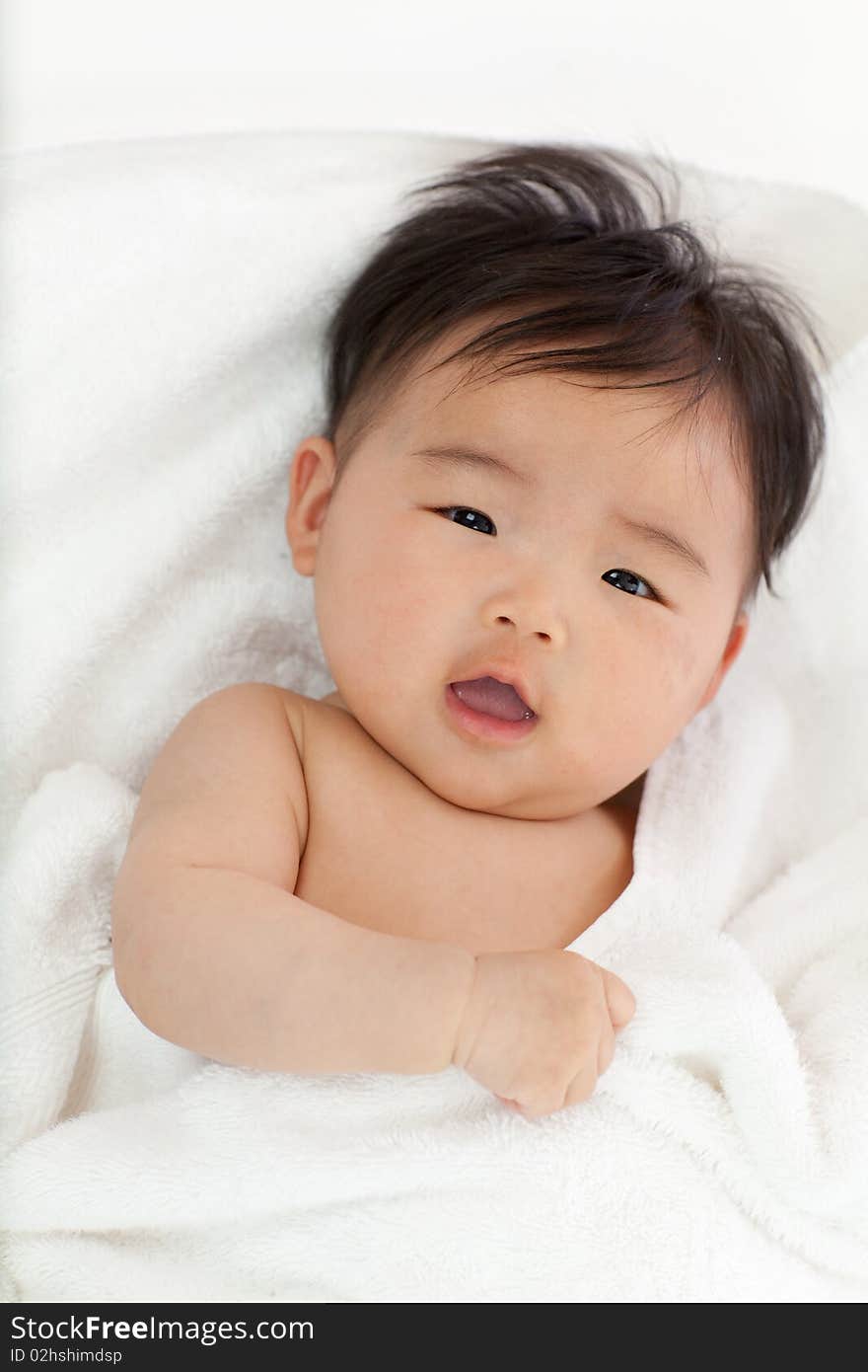 A smiling baby looking at the camera with her mouth open.