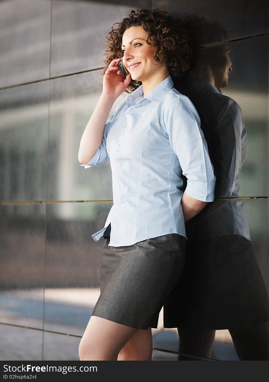 Italian businesswoman talking on mobile phone outdoors and smiling. Vertical shape. Italian businesswoman talking on mobile phone outdoors and smiling. Vertical shape