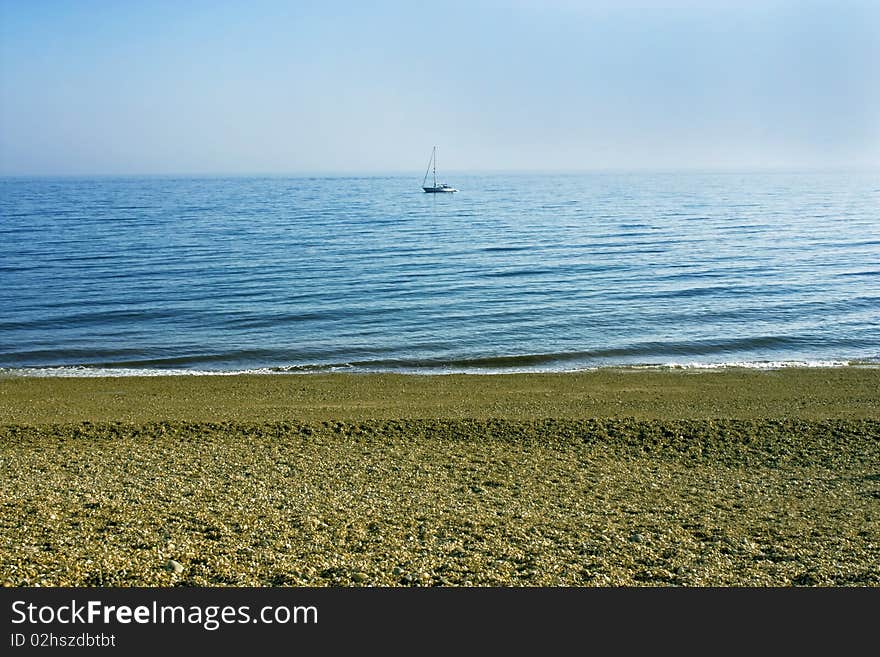 A far off yacht on a peaceful blue sea. A far off yacht on a peaceful blue sea