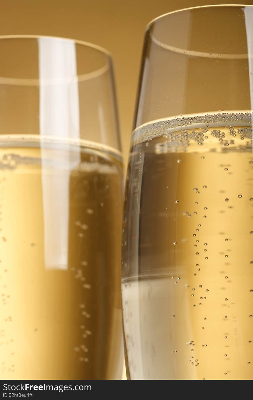 Two flutes with champagne on golden background. Two flutes with champagne on golden background