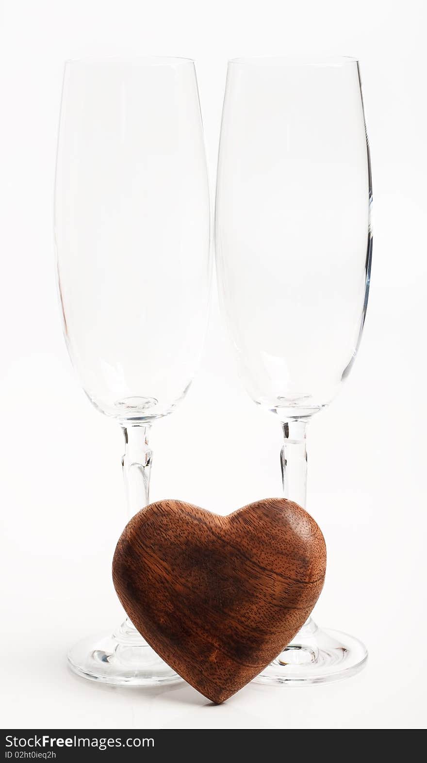 Two flutes lying on white underground with a wooden heart. Two flutes lying on white underground with a wooden heart